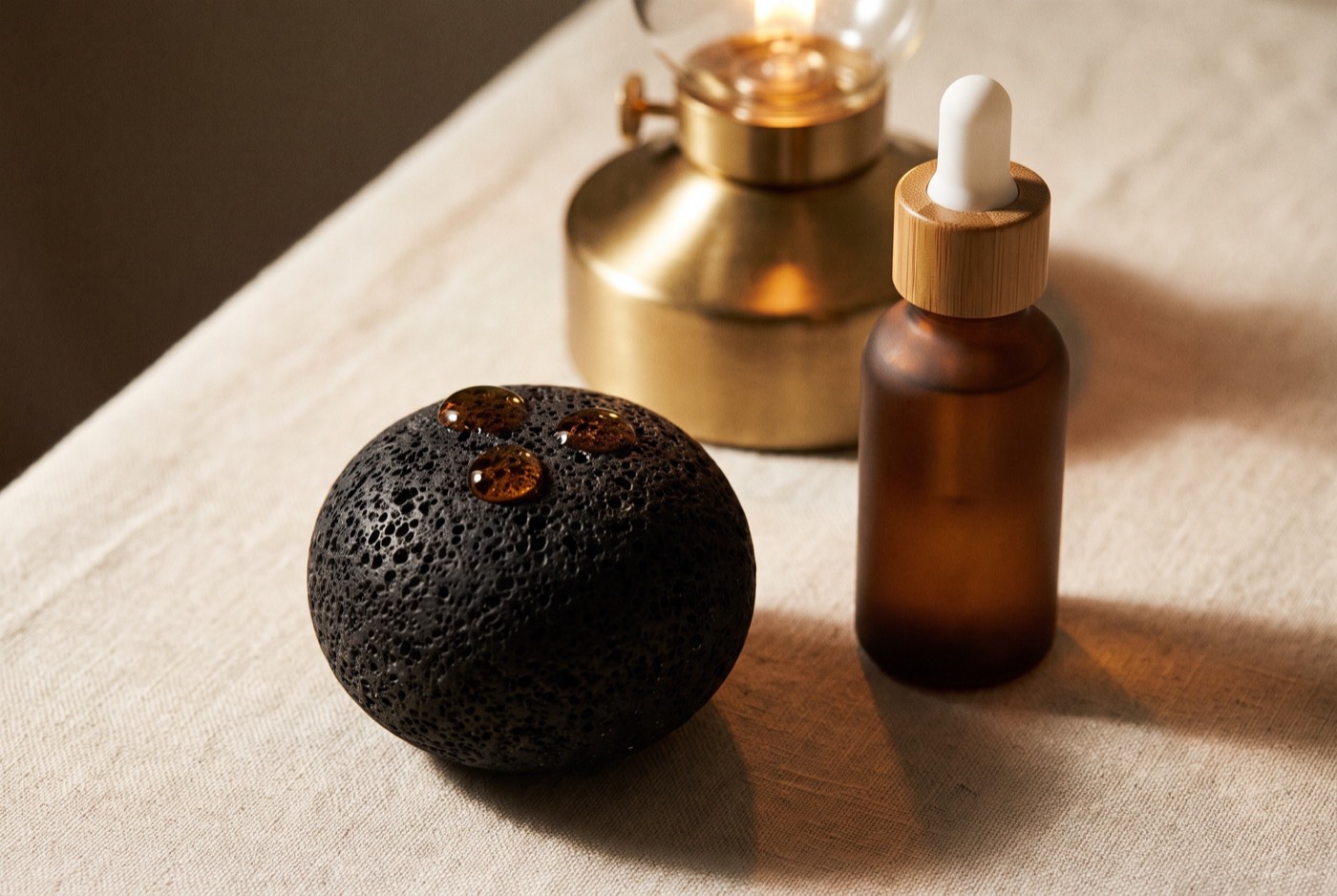 A volcanic stone with oil beside an amber bottle, lamp turned low